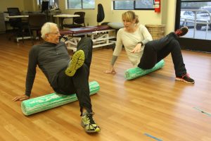 man and woman using yoga rollers to stretch
